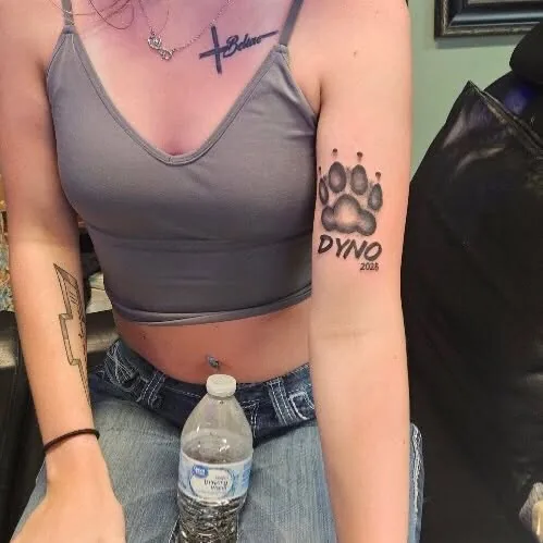 Paw print memorial tattoo on an outer arm
