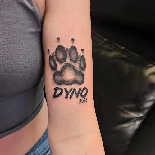 Paw print memorial tattoo with a name and year