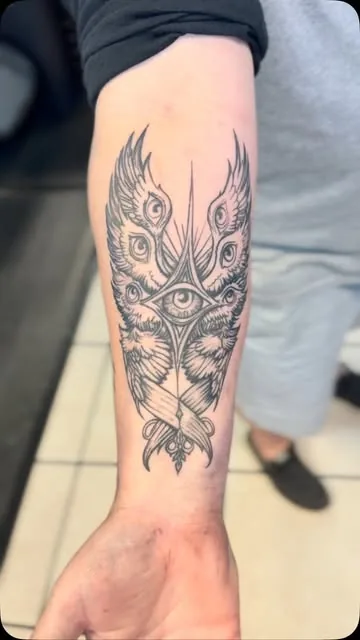 Ornamental eye and peacock feathers on a forearm