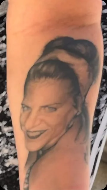 Black and grey portrait tattoo on a forearm